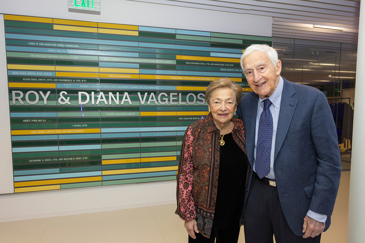 Diana and Roy Vagelos in front of a green and yellow colored wall that reads Roy & Diana Vagelos