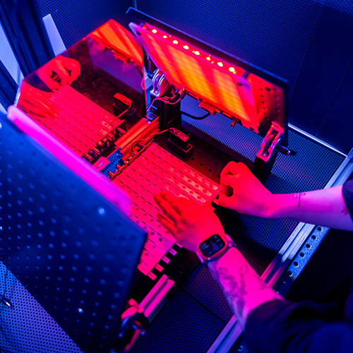 Hands in a three-sided box with flourescent lights glowing. 