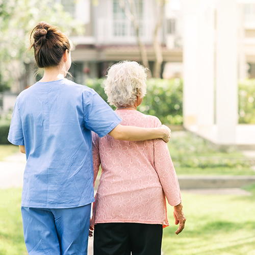 Nurse caregiver support walking with elderly woman outdoor