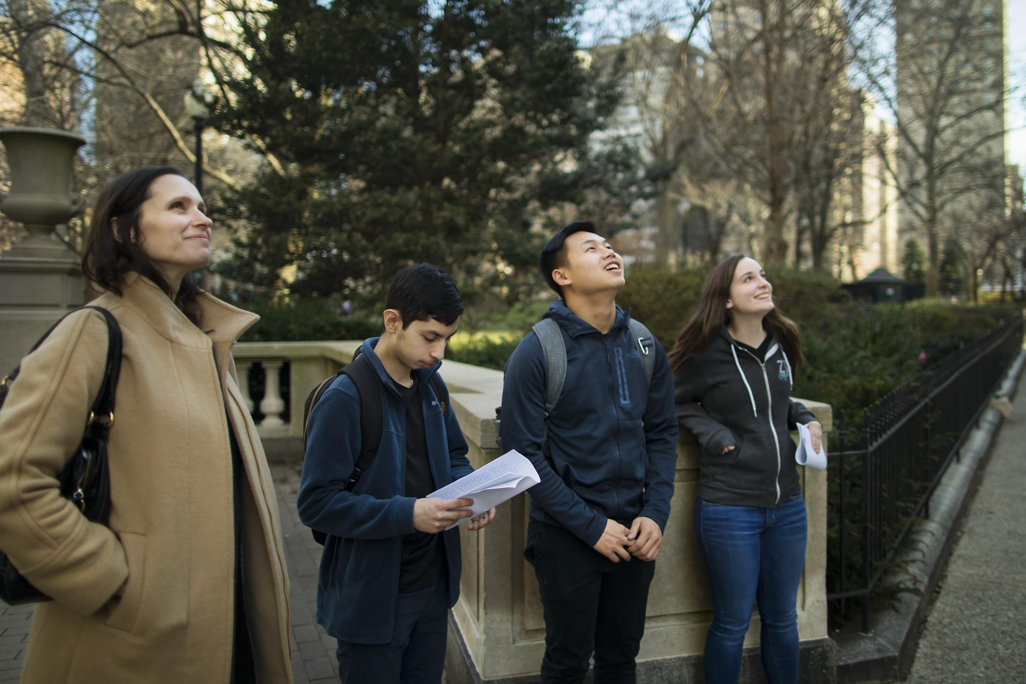 Mary Caldwell at left, with three students, standing outside and looking up at something out of sight 