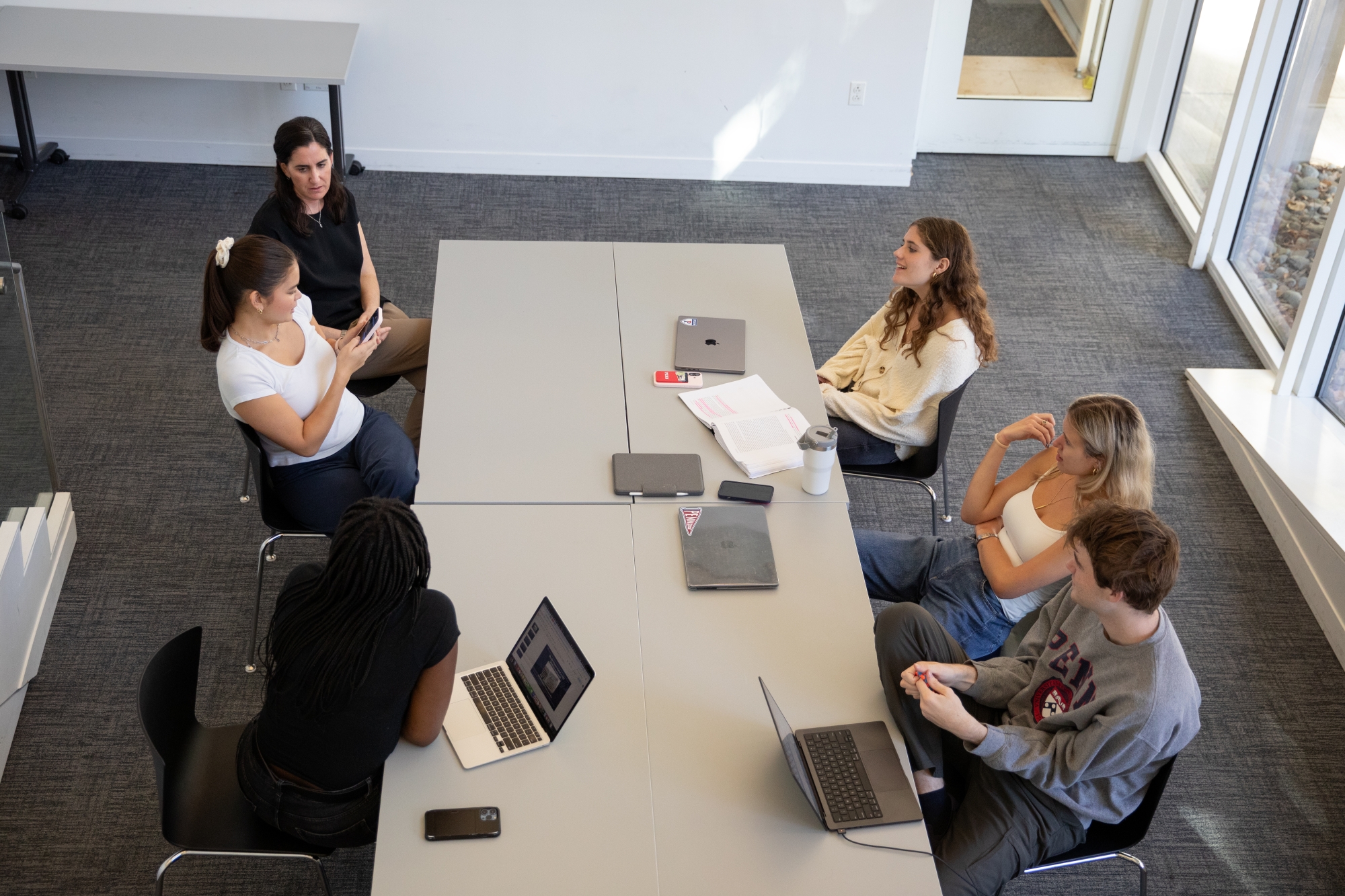 An overhead view of a group of people sitting around a table engaged in conversation.