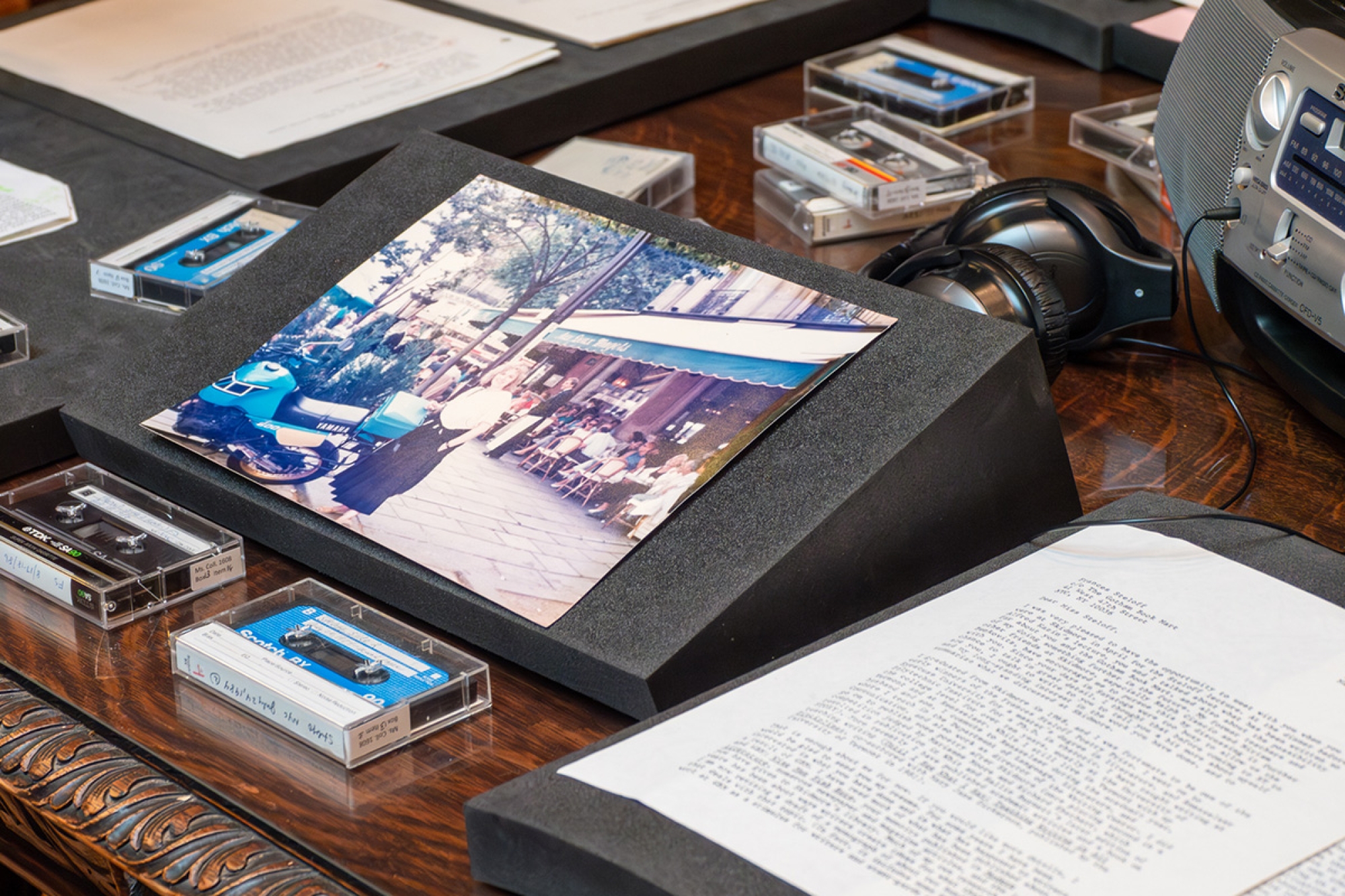 Materials on a table including several casette tapes and a tape player, as well as a faded color photograph. 